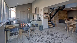 A modern kitchen with a dining area, a staircase, and a living room with a stone wall. - Spacious and bright family accommodation in Chazelles-sur-Lyon (Chazelles-sur-Lyon)