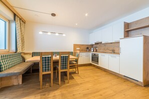A modern kitchen with a wooden bench seating area, white cabinets, and a built-in oven.