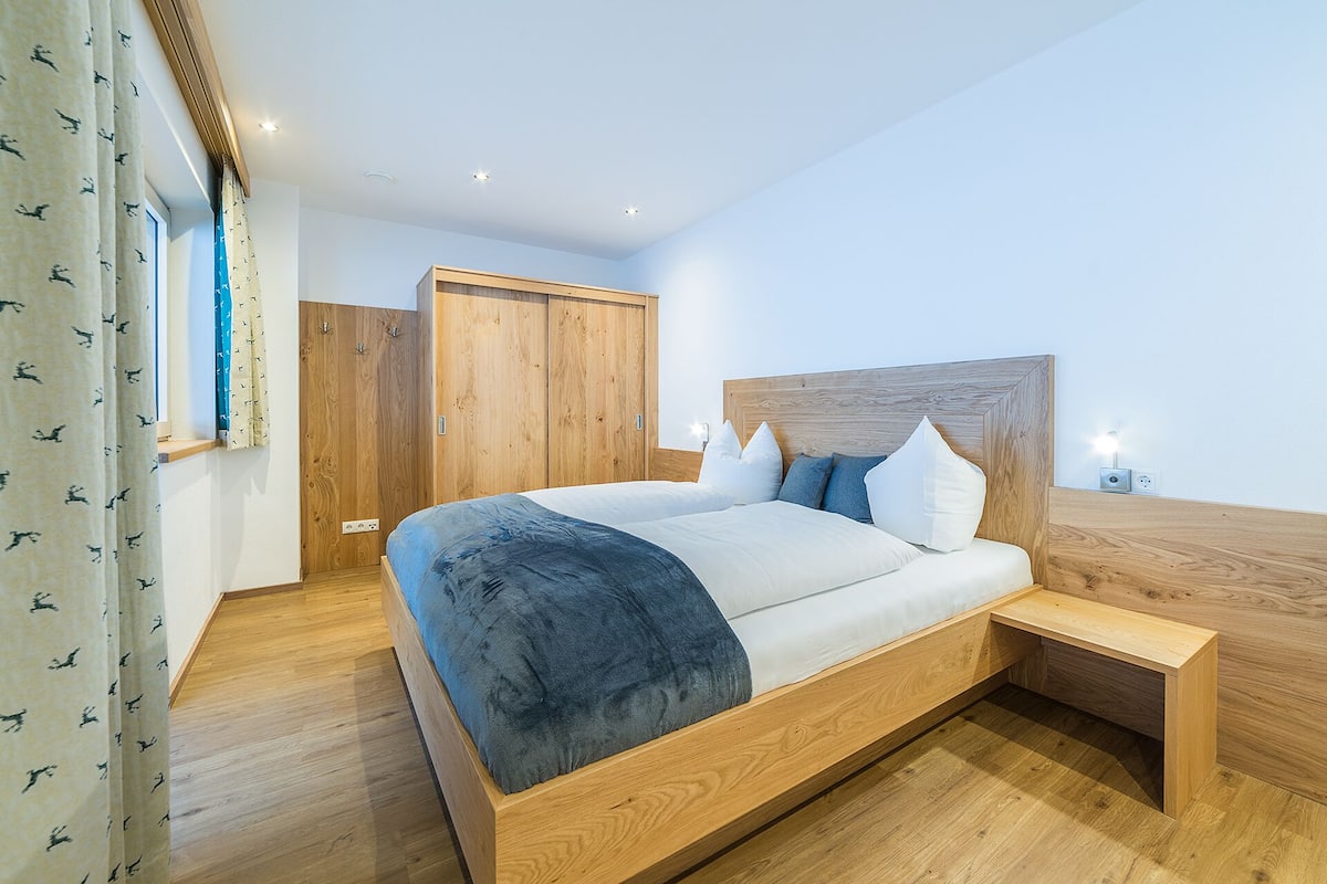 Un dormitorio moderno con un marco de cama de madera, una mesita de noche y un armario.