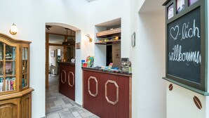 A reception area with a wooden cabinet, a counter with various items, and a chalkboard with 'Hello welcome' written on it.