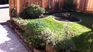 A garden with raised beds, a wooden fence, and a circular flower bed.