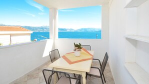 A balcony with a table and chairs, a potted plant, and a view of the sea and mountains. - PETRA ARBANIJA - apt for 5+1 just few steps from the beach (Arbanija)