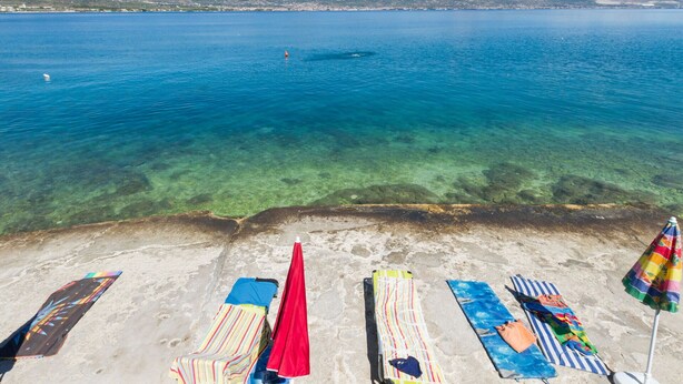 A beach with clear blue water, a sandy shore, and lounge chairs with umbrellas. - PETRA ARBANIJA - apt for 5+1 just few steps from the beach (Arbanija)