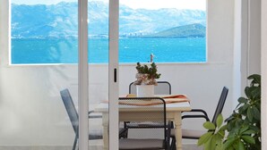 A dining area with a table and chairs, a potted plant, and a view of a body of water and mountains. - PETRA ARBANIJA - apt for 5+1 just few steps from the beach (Arbanija)