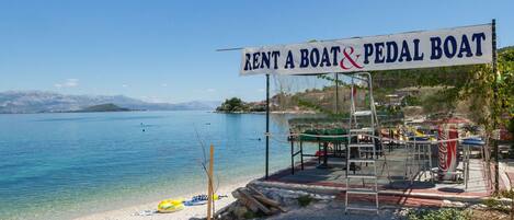 A beachside rental area with a sign for boat and pedal boat rentals.