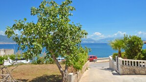 A coastal road with a view of the sea and mountains. There are parked cars and a stone wall with a gate. - PETRA ARBANIJA - apt for 5+1 just few steps from the beach (Arbanija)