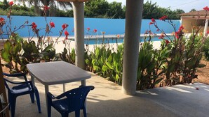 A patio area with a table and chairs, surrounded by plants and a blue wall. - Séné-Marra haven of peace.  (Cap Skirring)