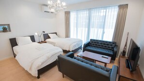 Een hotelkamer met twee bedden, een bank, een televisie en een kroonluchter.
