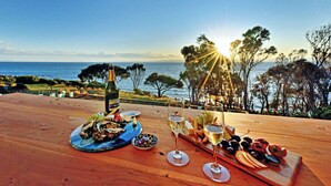 A wooden table with a bottle of champagne, oysters, and a variety of snacks and drinks. - Freycinet Coastal Retreat - Freycinet Holiday Houses (Coles Bay)
