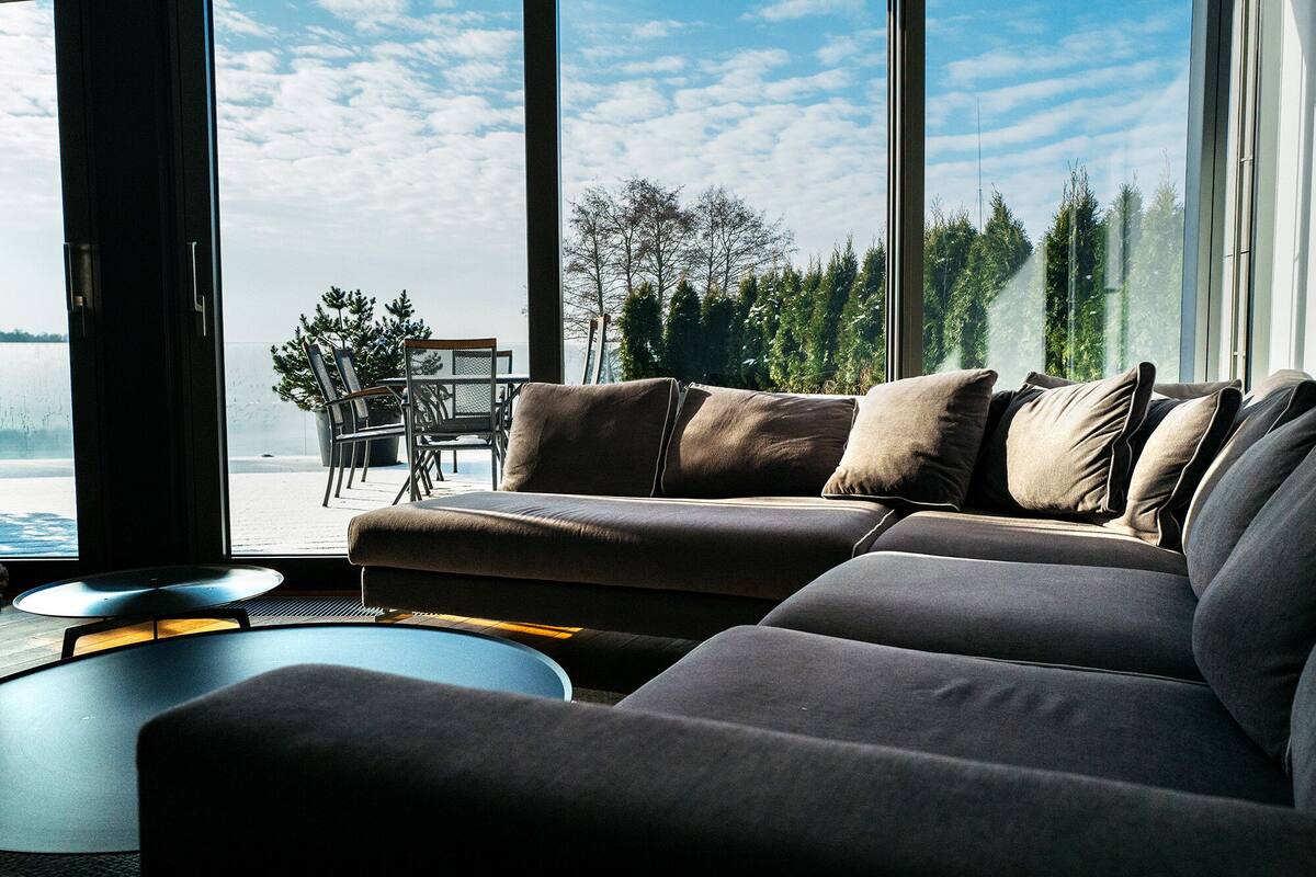 A modern living room with a large window, a sofa, and a dining area with chairs and a table.