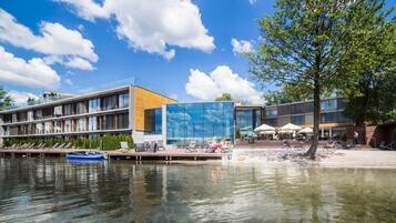 Enjoy waterfront views and a relaxing atmosphere at this hotel, featuring a glass facade and outdoor seating areas.