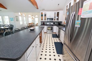 A kitchen with white cabinets, a stainless steel refrigerator, and a black and white tiled floor.