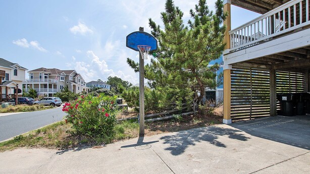 Un barrio residencial con un aro de baloncesto, casas y un garaje.