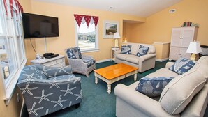 A living room with a flat-screen TV, two sofas, a coffee table, a wicker chair, and a cabinet. - Oceanside, Private Pool, Close to Beach Access and Shopping! KH1, Marabel-by-the-Sea (Kitty Hawk)