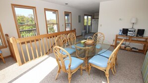 A dining area with a glass table, wicker chairs, and a view of the outdoors through large windows. - Oceanside, Community Pool, Community Tennis, PT7, Summer Winds (Duck)