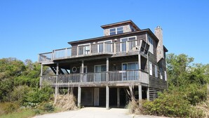 A two-story wooden house with a balcony on the second floor, a chimney, and a door leading to a covered area. - Oceanside, Community Pool, Community Tennis, PT7, Summer Winds (Duck)