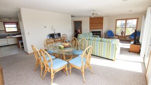 A spacious living area with a dining table surrounded by wicker chairs, a striped sofa, and a television. - Oceanside, Community Pool, Community Tennis, PT7, Summer Winds (Duck)
