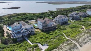 Vista aerea di una zona residenziale costiera con diverse case, una piscina e una spiaggia.
