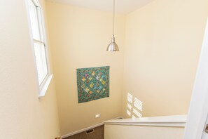 Una habitación con ventana, una lámpara de pared y un edredón colorido.