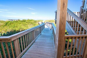 A wooden boardwalk leading to a beach with a clear sky.