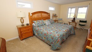 Une chambre à coucher avec un lit en bois, une table de chevet, une lampe, une chaise et une petite table.