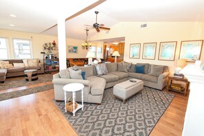 A spacious living room with a sectional sofa, a dining area, and a kitchen in the background.