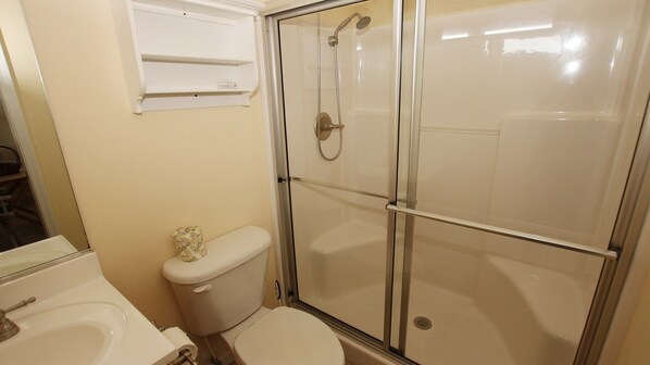 Une salle de bain comprenant des toilettes, un espace douche et un lavabo.