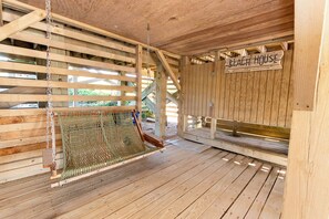 Une structure en bois sur laquelle est accrochée une enseigne indiquant « Maison de plage », et un hamac suspendu au plafond.