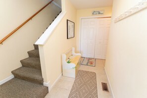 A staircase with carpeted steps leading to a door with a 'Welcome to the Beach House' sign above it.