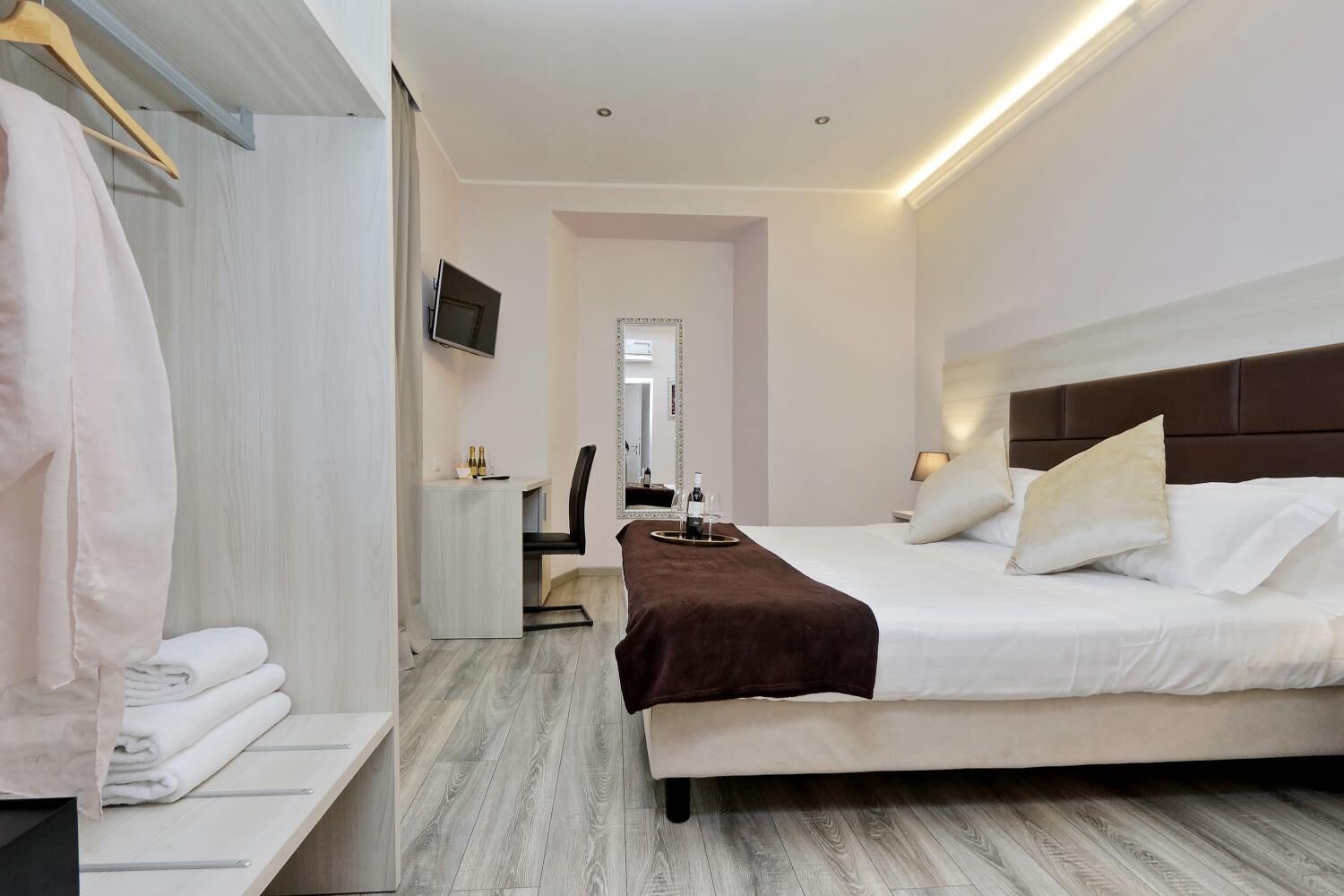 A modern hotel room with a bed, bedside table, and a mirror.