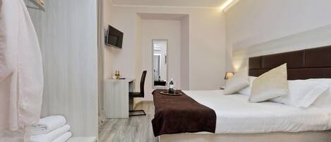 A modern hotel room with a bed, bedside table, and a mirror.