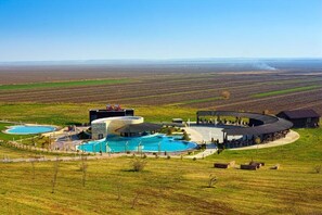 A resort with a circular pool, outdoor seating, and a view of the surrounding fields.