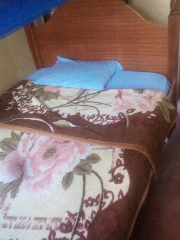 A bed with a floral bedspread and two pillows. - 77 Guest House (Kitui)