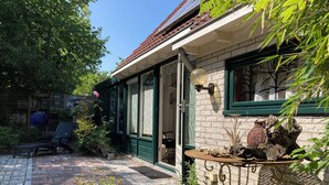 A brick patio with a potted plant, a bench, and a rustic outdoor table. - 5 Pers - Equipped House Gudrun With Sauna - Dogs are Welcome (Anjum)