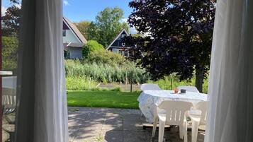 An outdoor patio area with a table and chairs, a garden view, and a building in the background.