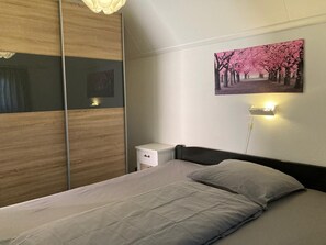 A bedroom with a bed, bedside table, and a wall-mounted picture. - Charming Bungalow Rental in Anjum With River Views (Anjum)