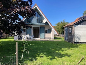 A two-story house with a balcony, a fenced yard, and a small shed. - Charming Bungalow Rental in Anjum With River Views (Anjum)