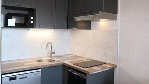A compact kitchen with a dishwasher, sink, and microwave. - Charming studio for 4 in the heart of Les Orres 1650 (Les Orres)