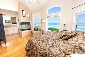 A bedroom with a large bed, a fireplace, a view of the ocean, and a kitchen area. - OCEANFRONT, Ocean Views, Pool, Rec Rm, PI244, Ashcroft (Corolla)