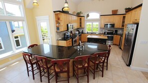 Una cocina moderna con una isla central, armarios de madera y electrodomésticos de acero inoxidable, con vistas al exterior.