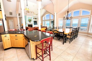 A spacious kitchen with a large island, a dining area with a view, and a living room with a fireplace. - OCEANFRONT, Ocean Views, Pool, Rec Rm, PI244, Ashcroft (Corolla)