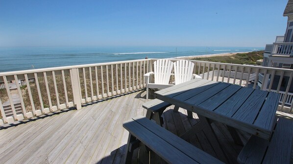 Una terraza de madera con vistas al océano y la playa.