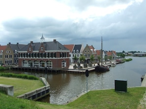A canal-side building with a traditional architectural style, featuring a prominent tower and large windows. - 6 Pers - Chalet Emma Located at the Lauwersmeer With own Fishing Pier (Anjum)