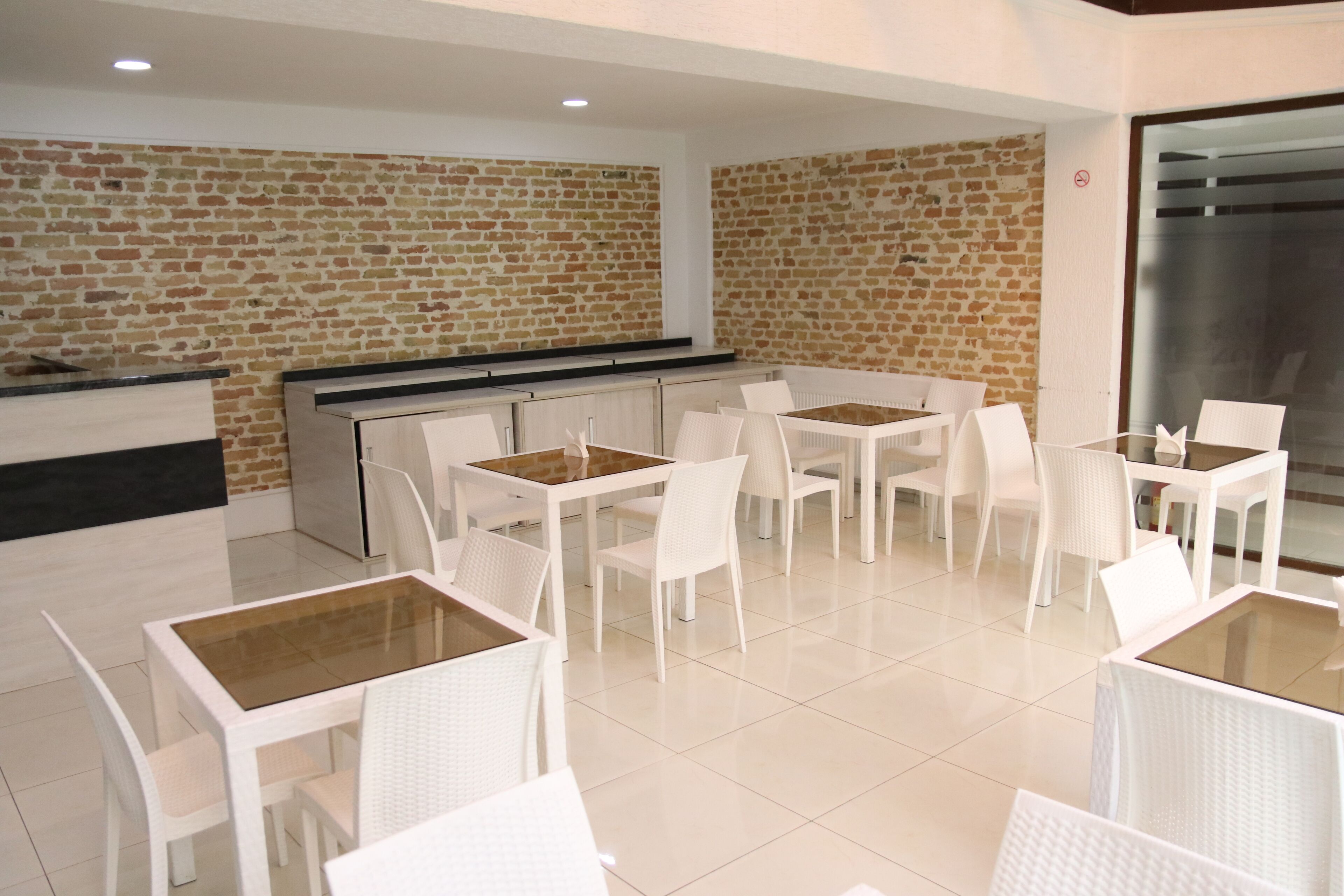 A modern dining area with white furniture and a brick wall backdrop.