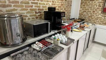 A buffet setup with a stainless steel cooler, microwave, and various food items on a counter.