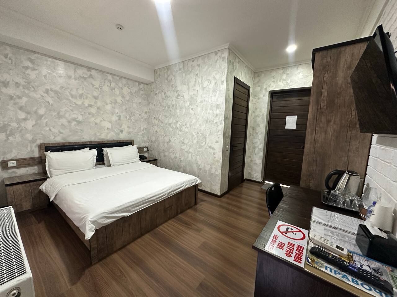 Una habitación de hotel con una cama, un escritorio con teléfono y un espejo.