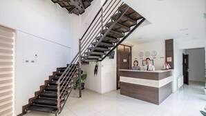 A modern hotel lobby with a staircase, reception desk, and a clock on the wall. - Orion Hotel (Tashkent)