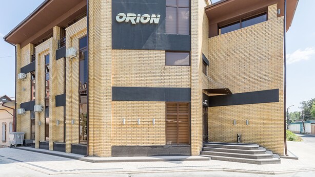 A modern building with a prominent "ORION" sign, featuring a brick facade and large windows. - Orion Hotel (Tashkent)