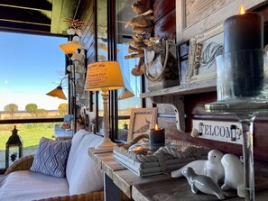 A cozy room with a wicker sofa, a 'WELCOME' sign, decorative items, and a view of the outdoors.