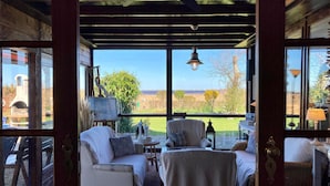 A cozy room with a view of the countryside, featuring a sofa, armchair, and a small table.